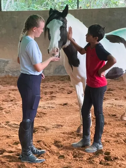 A young boy learns how to properly interact with and care for a horse under the guidance of an instructor. These moments are essential for building confidence and a respectful partnership with these magnificent animals.