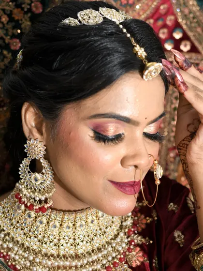 A close-up of a glamorous bridal look. The focus is on the shimmering cut-crease eye makeup and the intricate details of the jewelry and hair.