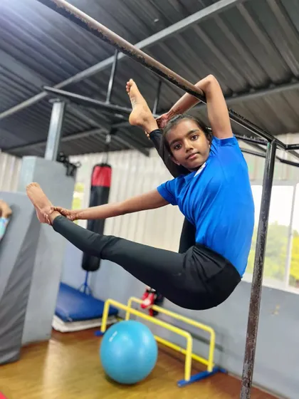 The aura of a confident athlete. This young gymnast holds an impressive split on the bar, showcasing both her strength and her amazing flexibility.