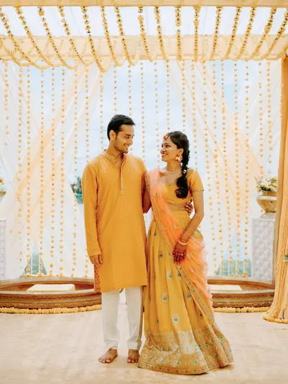 A sweet portrait of the couple standing under their beautiful Haldi mandap at Moongate venue.