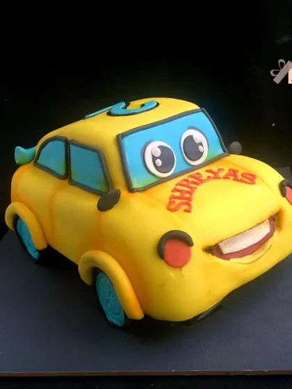 A 3D sculpted cake of a cute, smiling yellow car character.