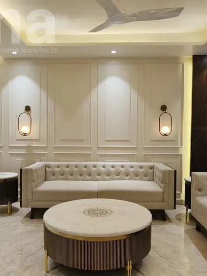 Timeless elegance is achieved by combining classic elements. Here, a Chesterfield sofa with traditional tufting is framed by modern rattan work and set against a wall with classic wainscoting, creating a look that is both sophisticated and fresh.
