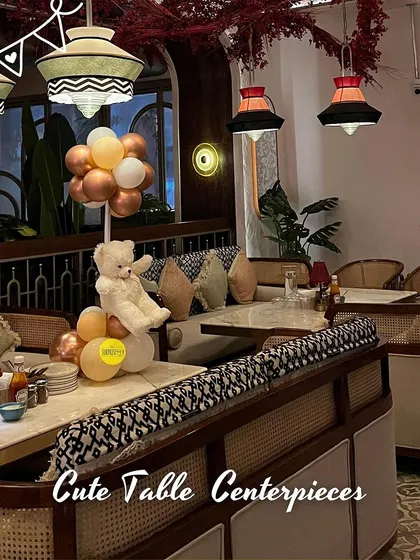 Cute table centerpieces, like this teddy bear sitting on a cloud of balloons, add a playful and charming touch to the seating arrangements at a baby shower.