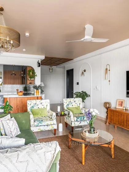 A wider view of the living room, showing how the floral armchairs, green sofa, and simple arch create a space that is full of color, texture, and personality.
