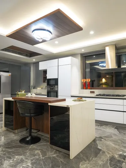 This angle shows the two-tiered island design, which includes a raised wooden bar for seating. This feature cleverly separates the cooking zone from the dining area.