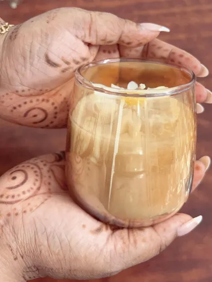Holding the beautiful daisy candle in a glass jar. My henna-adorned hands add a traditional touch to this modern candle.