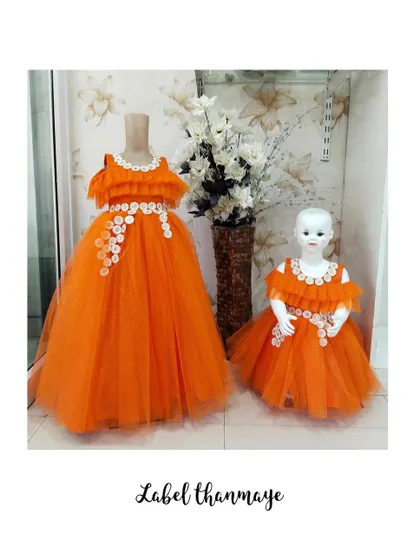 A bright orange twinning set on display. I created a full-length gown for the mother and a matching knee-length frock for the daughter, both with floral details.