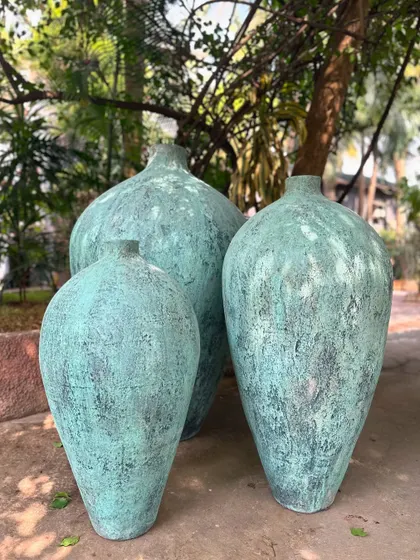 The 'Kembung' trio in a rustic teal finish, looking perfectly at home in a natural, outdoor setting.