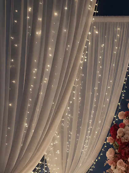 A detail shot of the fairy light curtains behind sheer white fabric. This technique creates a soft, diffused glow that adds to the romantic ambiance without being overpowering.