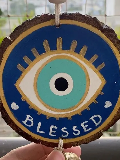 Another view of the "Blessed" evil eye hanging, showing the natural texture of the wood slice.
