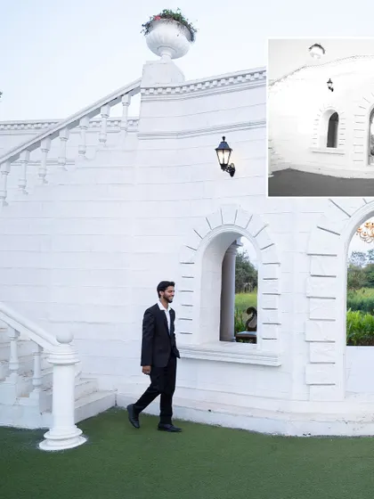 A stylish pre-wedding shot of the groom-to-be walking by a grand, white architectural setting, conveying a sense of modern elegance.