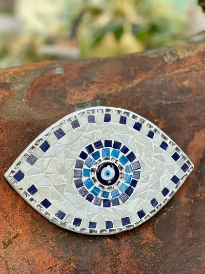 An evil eye amulet, handmade from mosaic tiles. This piece can add a pop of color to a garden nook or an indoor wall, while also offering its legendary protective qualities.