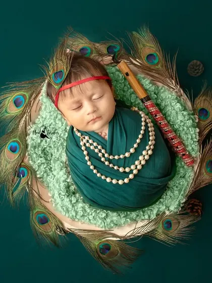 This serene portrait captures a sleeping newborn as Kanha, holding his flute. The composition is balanced and artistically styled.