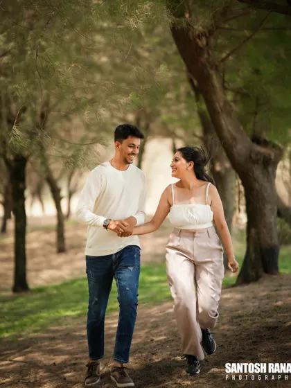 A happy, candid shot of a couple walking hand-in-hand through a park.