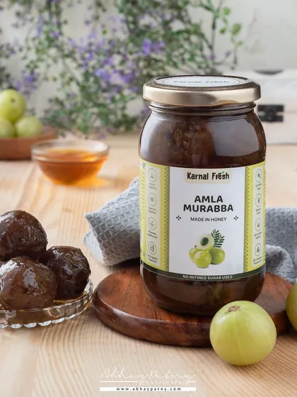 This shot for Amla Murabba uses natural light and wooden textures to convey a sense of wellness and purity. The fresh amla fruit is included to emphasize the natural origin of the product.
