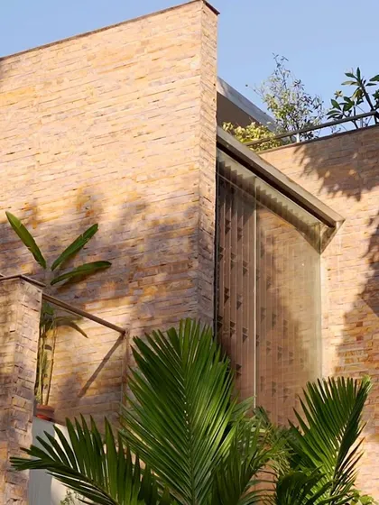 Another view of the stone-clad facade, highlighting the clean intersection between the solid wall and the glass windows, a hallmark of our contemporary design approach.