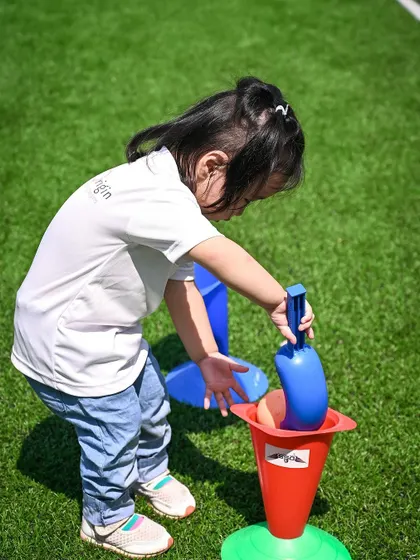 A child uses a shovel to place a ball into a cone, another variation of our sports day games.
