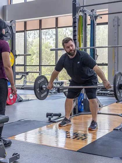 A trainee practices a barbell row, focusing on engaging the back muscles for optimal strength development.