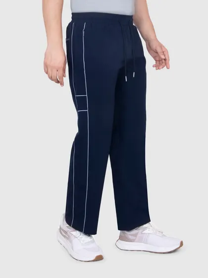 A side view of the sportswear track pants, highlighting the piping detail and the overall silhouette of the garment.