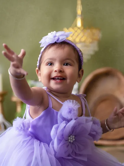 Reaching out with a happy smile. This pre-birthday shoot in a lovely lavender dress is a perfect way to celebrate turning one.
