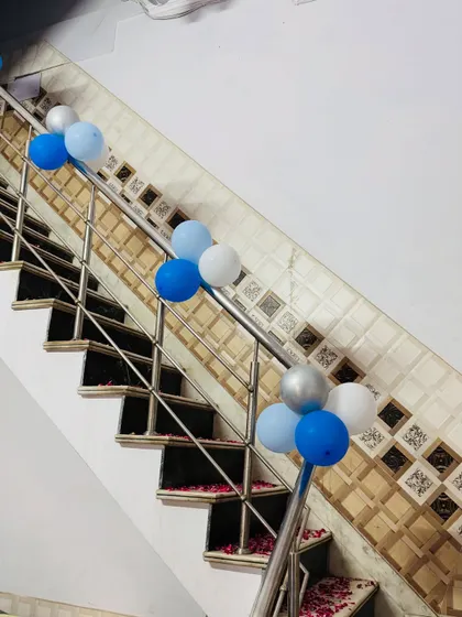 Simple and elegant 'Welcome Baby' decorations, with blue and white balloon clusters tied to the staircase railing.