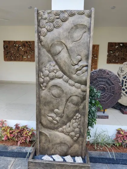 A large, vertical water feature with two Buddha faces carved in relief. This is a unique piece that combines art with the soothing sound of water.