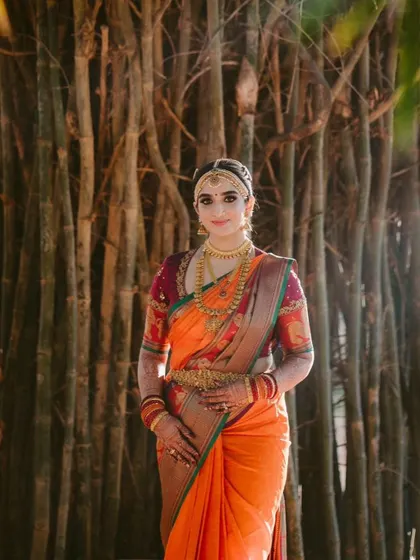 A full view of our bride Arpitha's stunning wedding attire. The vibrant orange Kanjeevaram paired with a rich purple blouse creates a striking and beautiful contrast.