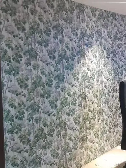 A full wall covered in a green forest-themed wallpaper, creating an immersive and natural environment in this office or study space.