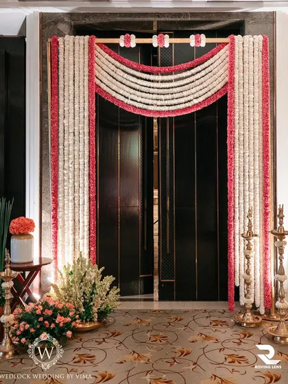 An elegant floral doorway created with jasmine and pink flower garlands for a traditional ceremony. This beautiful entrance sets a festive and welcoming tone for the event.