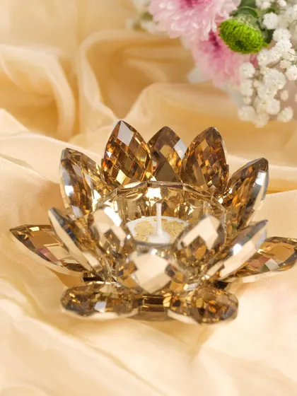 A single amber-colored crystal lotus tea light holder, capturing the light beautifully.