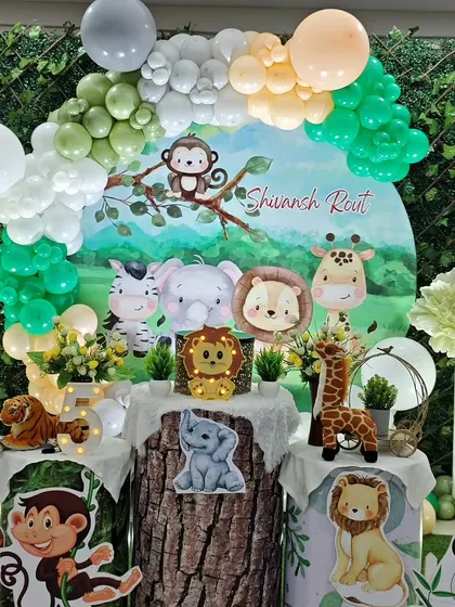 A beautiful and lush setup for Shivansh's 5th birthday, with a circular backdrop featuring cute jungle animals and a natural-toned balloon garland.