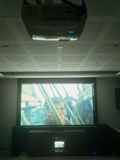 Here is a complete home theater system after a smooth and professional installation. The Epson projector is ceiling mounted, and the large fixed frame screen is flanked by powerful floor standing speakers and a dedicated AV console.