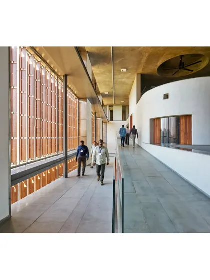 The circulation corridor at the JSW School of Public Policy is animated by the rhythmic pattern of light filtering through the facade's terracotta screens. This space is designed for movement and informal social exchange.