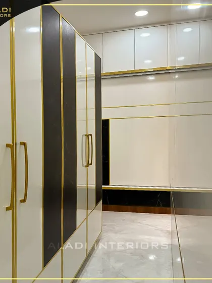 A stylish wardrobe with white and dark brown doors featuring elegant gold-colored handles and trim, offering a touch of luxury to the bedroom storage.