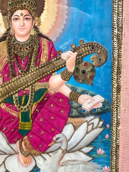 A detailed view of the embroidery on the Goddess Saraswati cloth oleograph. The careful selection of colors and materials adds a three-dimensional element that makes the artwork truly special.