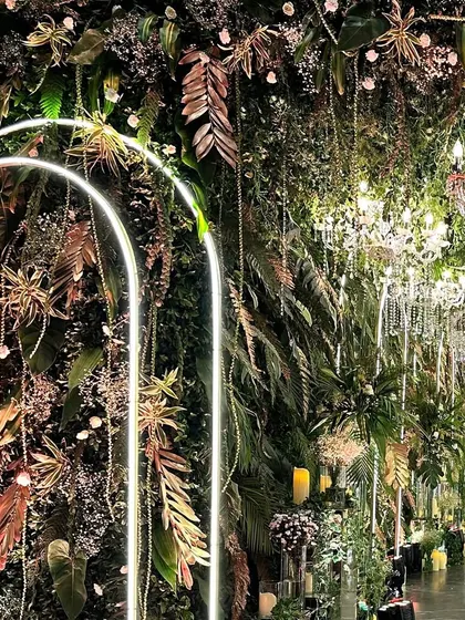 A stunning wall from the whimsical wild theme, featuring a dense layer of tropical foliage, illuminated arches, and hanging crystal chains.