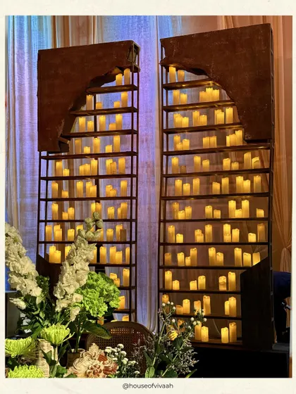 Our signature candle walls, featuring hundreds of glowing pillar candles set within arched metal frames, creating a dramatic and romantic backdrop.