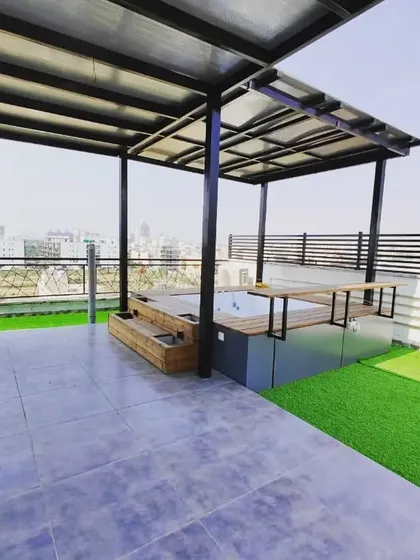 This wide shot shows the complete jacuzzi setup, situated under a covered pergola on a high-rise terrace, offering stunning city views while you relax.
