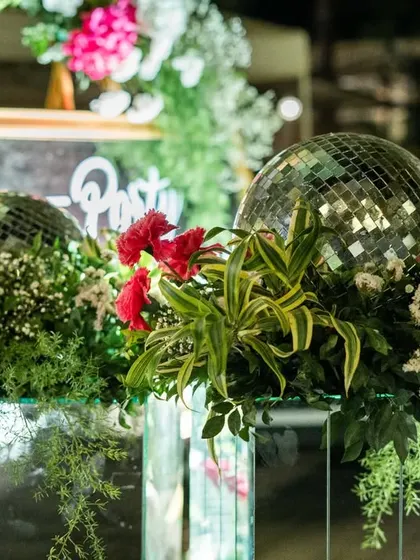 A close-up of the after-party decor, where disco balls are nestled among fresh flowers on top of mirrored pedestals.