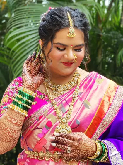 This bride is radiating elegance in her pink and purple Paithani saree. The makeup is soft and glowing, with beautiful henna and traditional green bangles completing the look.