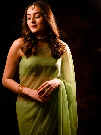 A three-quarter shot showing the full drape of the green saree. The mood is serene and graceful.