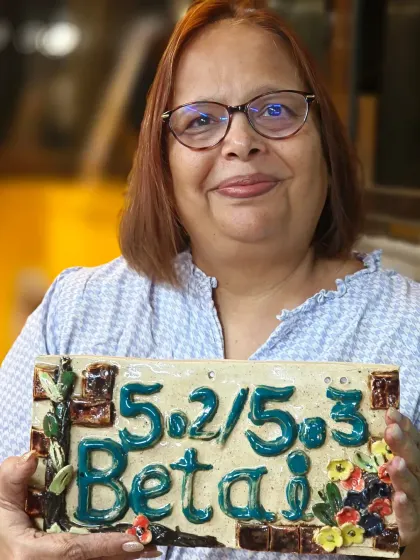 A student proudly displays the decorative ceramic nameplate she designed and created for her home. Our courses empower you to make personalized, functional art.