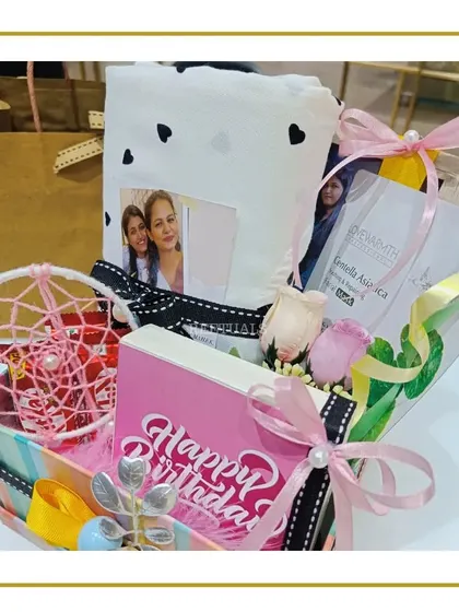 A closer look at the colorful birthday hamper, showing the 'Happy Birthday' sign, dreamcatcher, and personalized photo frame in a rainbow-striped box.