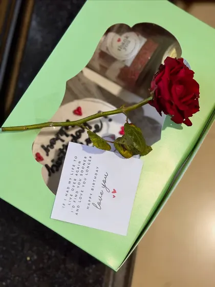 A romantic birthday package showing a bento cake and cake jars inside a gift box, complete with a single red rose and a heartfelt "love you" note.