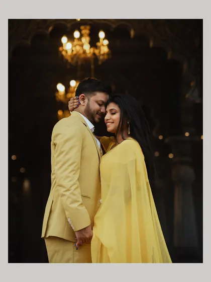 An elegant portrait of the couple embracing under a chandelier, their yellow outfits glowing in the warm light.
