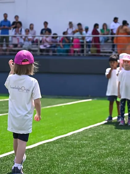 A student leads her team, holding the school flag at the start of the sports meet.