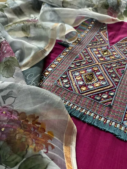 A detailed shot focusing on the intricate mirrorwork and thread embroidery of the kurta's yoke, set against the soft floral print of the dupatta.