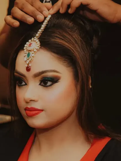 A close-up of the hairstylist placing the maang tikka, a crucial part of the bridal shringaar.