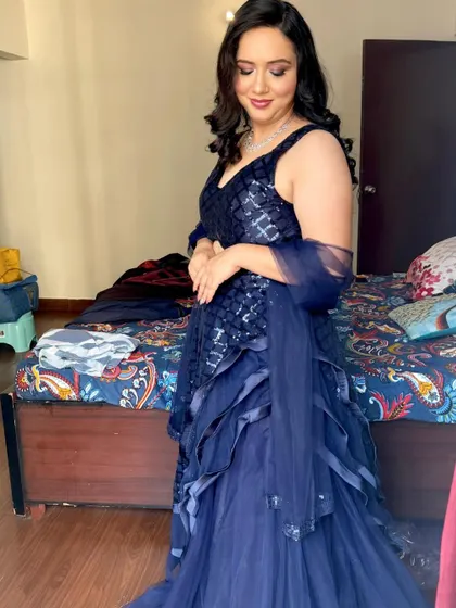 A client looking beautiful in a navy blue sequin lehenga for a party. The makeup is soft and glowing, with loose curls.