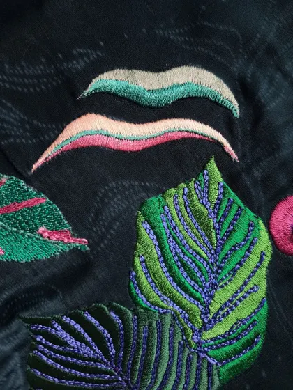 Another detail of the nature-inspired embroidery, showing the different textures and colors used to create a lifelike and artistic representation of foliage.